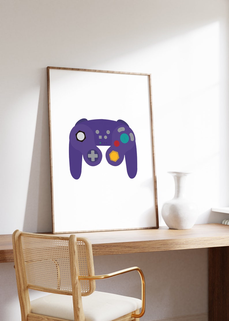 Puede incluir: Una impresi&oacute;n enmarcada de un mando de videojuego morado sobre un fondo blanco. El mando tiene un bot&oacute;n amarillo, rojo y azul.