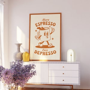 May include: A framed print with a cartoon illustration of a coffee cup with a face and arms. The text on the print reads "More Espresso Less Depresso".