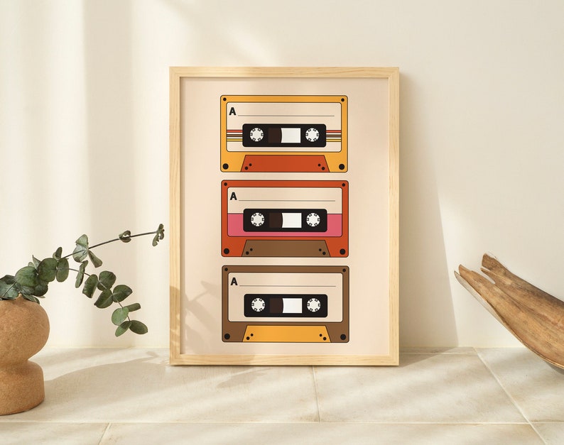May include: A framed print with a retro design featuring three vintage cassette tapes with the letter "A" on each. The tapes are in shades of yellow, orange, red, brown, and pink.
