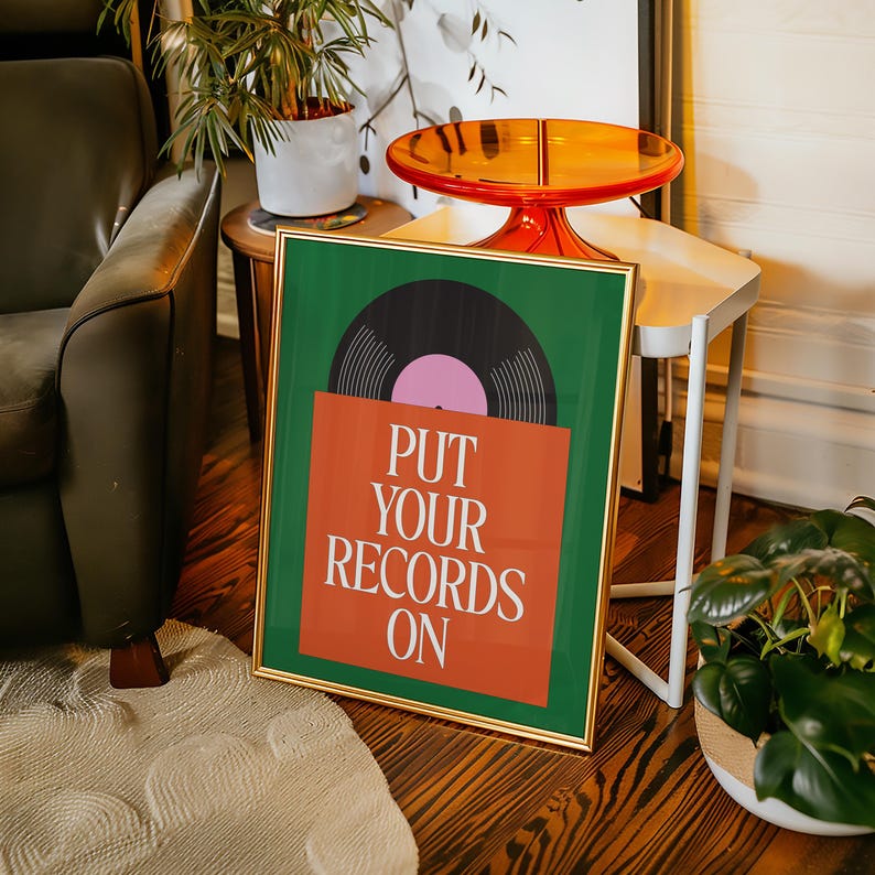 May include: Framed art print featuring a vinyl record design. The artwork has a green background with an orange record sleeve and a black record with a pink center. The text "PUT YOUR RECORDS ON" is displayed on the sleeve.