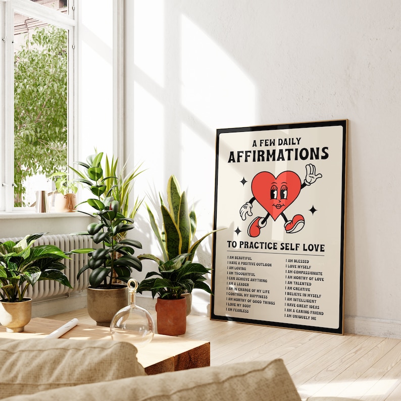 May include: A framed poster with the text "A Few Daily Affirmations To Practice Self Love" and a cartoon heart character. The poster is in a room with plants and a window.