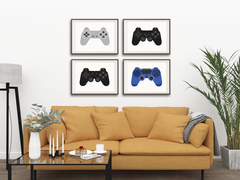 May include: Four framed prints of different colored video game controllers. The controllers are gray, black, blue, and white. The prints are hanging on a white wall above a yellow couch.