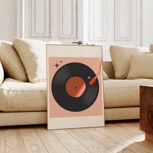 May include: A framed print of a black vinyl record with a red and orange center, on a pink background with two white stars. The needle is shown in a red and pink color.