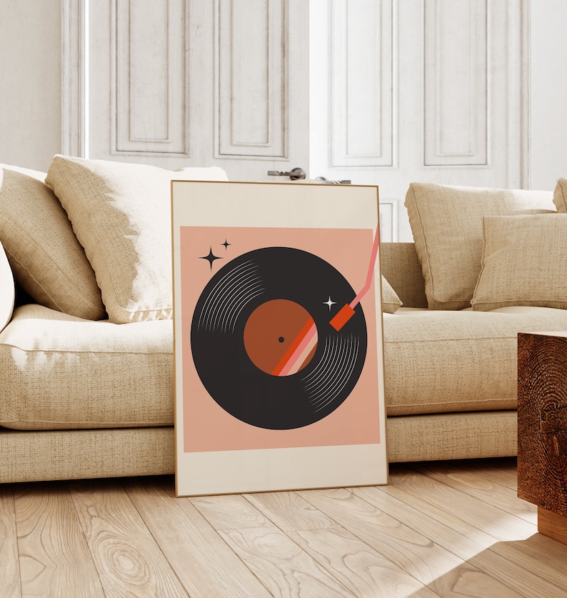 May include: A framed print of a black vinyl record with a red and orange center, on a pink background with two white stars. The needle is shown in a red and pink color.