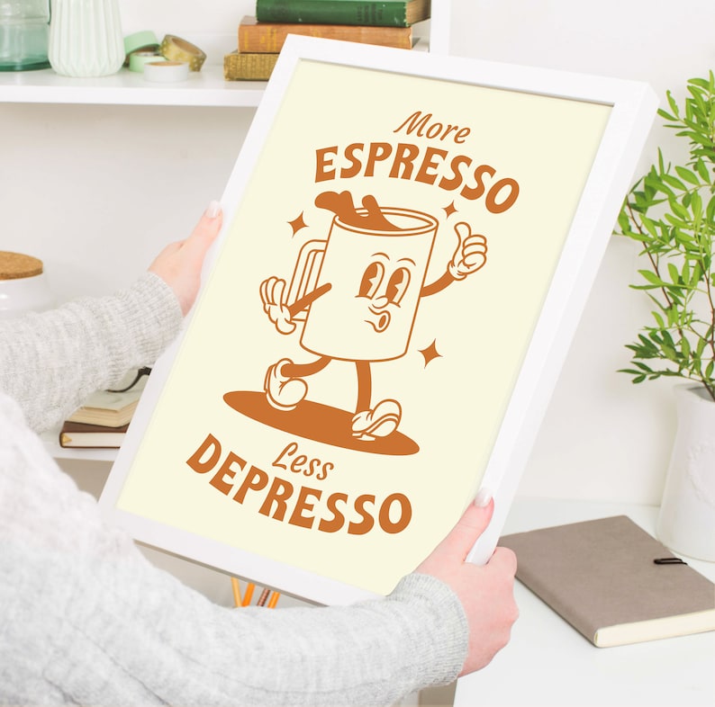 May include: A white framed print with a cartoon illustration of a coffee cup with a face and arms and legs. The text on the print reads "More Espresso Less Depresso".