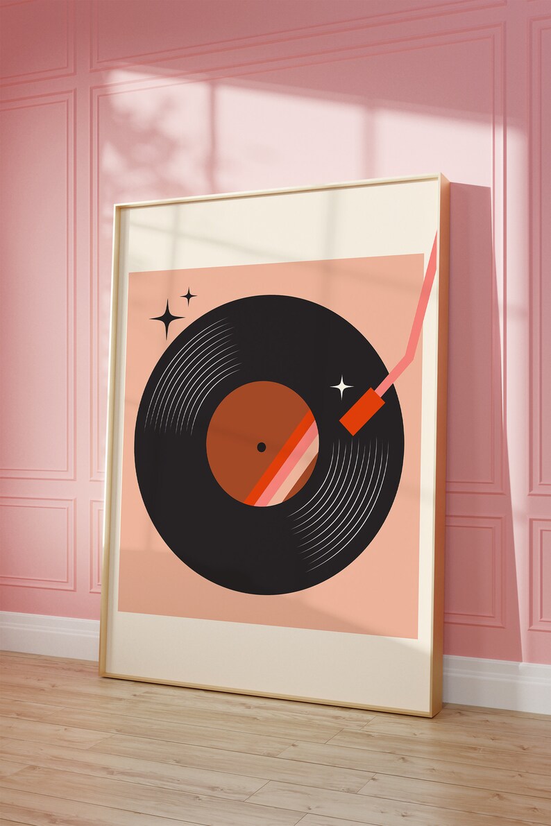 May include: A framed print of a black vinyl record with a red and orange center, a red needle, and two white stars on a peach background.
