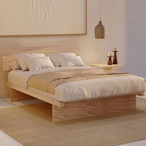 May include: A low-profile platform bed frame constructed from light-toned wood with a prominent grain pattern. The bed features a rectangular headboard, a solid base, and is dressed with white pillows and a beige blanket, creating a neutral aesthetic.