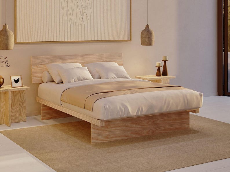 May include: A low-profile platform bed frame constructed from light-toned wood with a prominent grain pattern. The bed features a rectangular headboard, a solid base, and is dressed with white pillows and a beige blanket, creating a neutral aesthetic.