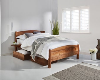 May include: A wooden bed frame with a warm brown finish, featuring a curved headboard and integrated storage drawers underneath. The bed is dressed with white linens, grey pillows, and a textured grey throw blanket, creating a functional sleeping space.