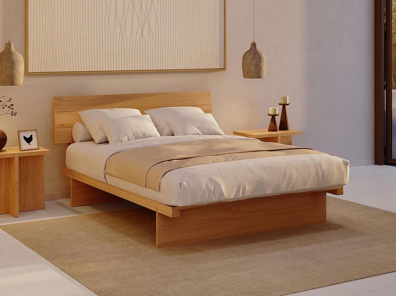 May include: A low-profile platform bed frame crafted from light-toned wood, featuring a horizontal slatted headboard. The bed is dressed with white pillows, a white duvet, and a tan runner, flanked by two matching wooden nightstands with candles.
