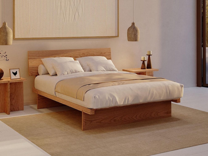 May include: A low-profile wooden bed frame with a horizontal slat headboard, featuring a white mattress, a beige runner, and two white pillows. The bed is flanked by two wooden side tables, each holding a candle, with two hanging pendant lights.