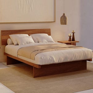 May include: A low-profile wooden platform bed frame with a horizontal slat headboard, featuring a white mattress, white pillows, and a beige runner. The bed is positioned on a large beige area rug, flanked by two wooden side tables with candles.