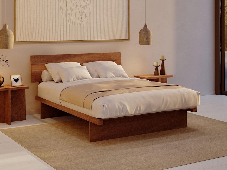 May include: A low-profile wooden platform bed frame with a horizontal slat headboard, featuring a white mattress, white pillows, and a beige runner. The bed is positioned on a large beige area rug, flanked by two wooden side tables with candles.