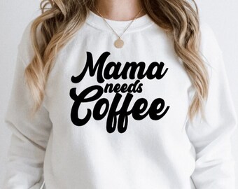May include: White sweatshirt with black text that reads "Mama needs Coffee" in a cursive font.