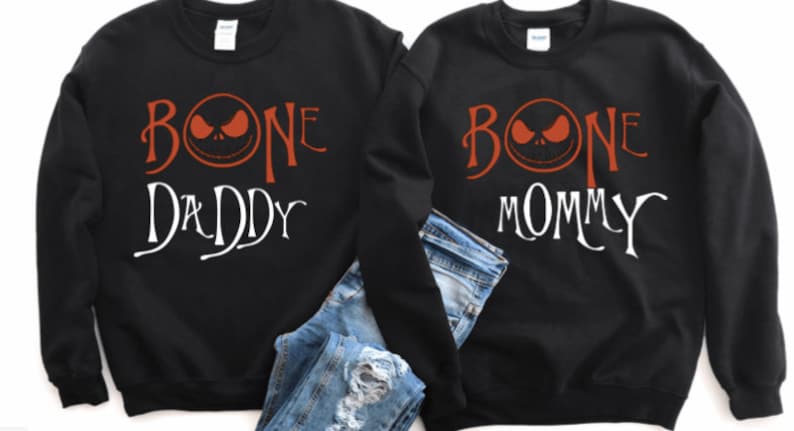 May include: Two black sweatshirts with a white graphic print of a cartoon character's face with the text "BONE DADDY" and "BONE MOMMY" in orange.