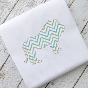 May include: A white fabric with a blue and green chevron patterned lion silhouette embroidered on it.