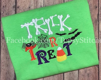 May include: A green t-shirt with an embroidered design that says "Trick or Treat" with a spider, web, bats, and candy corn.