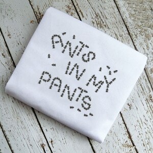 May include: White t-shirt with the text "ANTS IN MY PANTS" spelled out using ants.