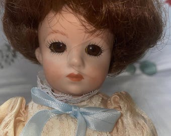 11 inch marked fully jointed and tightly strung porcelain doll wearing period 2-piece wedding dress with socks shoes and stand