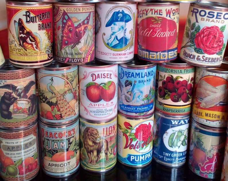 Puede incluir: Una colecci&oacute;n de latas vintage con etiquetas coloridas que muestran im&aacute;genes de mariposas, pavos reales, frutas y otros dise&ntilde;os. Las etiquetas incluyen texto como "Butterfly Brand", "Golden Pumpkin", "Defy the World", "Rose Brand", "Daisee Apples", "Dreamland Brand", "California Fruit Raspberries", "Peacocks Jam", "Lion Brand", "Velvet Pumpkin", "Tiny Green Lips" y "Clark, Mason & Co."