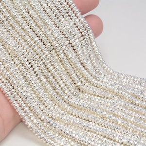May include: A strand of silver-toned faceted beads. The beads are small and round, and they have a shiny, metallic finish.