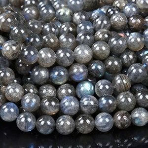 Puede incluir: Una hebra de cuentas redondas de piedra preciosa de labradorita gris. Las cuentas tienen un brillo iridiscente con destellos de azul y verde.