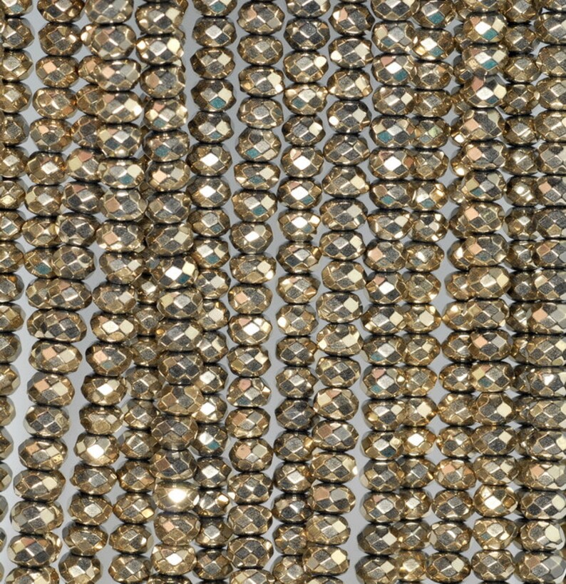 May include: Close-up of multiple strands of faceted, golden-colored beads. The beads are oval-shaped with multiple facets, creating a sparkling effect. The beads are strung together, forming vertical lines. Ideal for jewelry making.