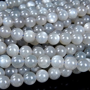 May include: A strand of white moonstone beads. The beads are round and have a smooth, polished finish. They are strung on a clear elastic cord.