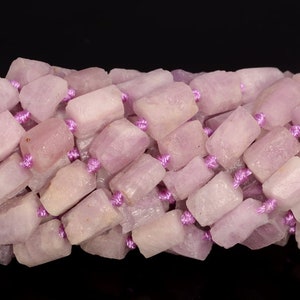 May include: A strand of pink and white gemstone beads, each bead is a rectangular shape with a rough, natural finish. The beads are strung on a purple cord.