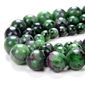May include: A close-up shot of a string of gemstone beads. The beads are predominantly green with dark green and maroon markings. The beads are of varying sizes and are strung together, giving a natural and organic appearance.