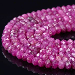 May include: A strand of pink ruby beads, each bead is faceted and has a slightly irregular shape.