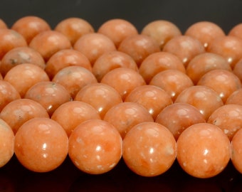 May include: A strand of smooth, round, orange carnelian beads. The beads are all approximately the same size and have a slightly translucent appearance.