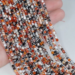 May include: A strand of round, multi-colored agate beads. The beads are a mix of white, orange, red, and black. The beads are approximately 4mm in diameter.