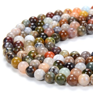 May include: A strand of colorful agate beads, featuring a variety of brown, green, white, and orange tones. The beads are round and smooth, with a natural, polished finish.