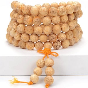 May include: A wooden prayer bead necklace with a knotted tassel. The beads are light brown and have a textured surface. The tassel is orange.