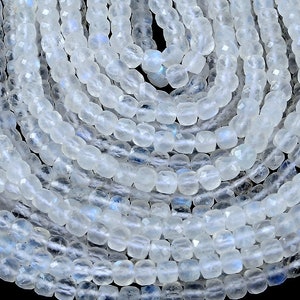 May include: A strand of white moonstone beads, faceted and polished, with a subtle iridescent shimmer. The beads are approximately 4mm in size and are strung on a clear elastic cord.