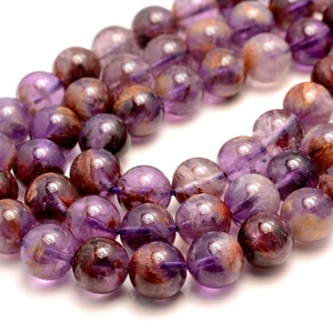 May include: A strand of round, purple amethyst beads with brown and gold inclusions. The beads are smooth and polished, and they have a natural, organic look.