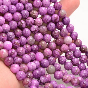 May include: A strand of purple and white marbled round beads. The beads are smooth and have a natural, organic look.