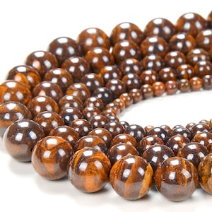 May include: A strand of brown and gold tiger iron beads, with a variety of sizes and shapes. The beads are polished and have a smooth, shiny finish.