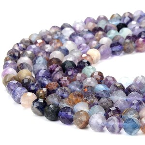 May include: A strand of faceted gemstone beads in shades of purple, blue, and brown. The beads are round and have a polished finish.