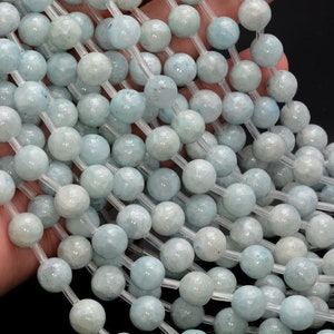 May include: A strand of light blue aquamarine beads, each bead is round and has a slightly textured surface.
