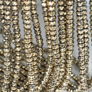 May include: Close-up of multiple strands of faceted, golden-colored beads. The beads are strung together, creating a textured and reflective surface. The beads are uniform in size and shape, and the overall effect is one of elegance and sophistication. Ideal for jewelry making.