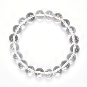 May include: A clear quartz crystal beaded bracelet with round beads. The bracelet is made of natural stones and is approximately 7 inches in length.