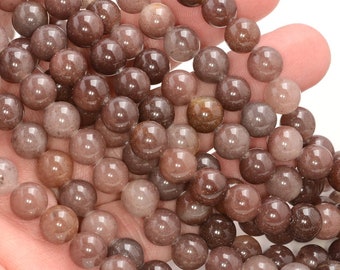 Puede incluir: Una hebra de cuentas redondas de piedra preciosa de color marrón y transparente. Las cuentas son translúcidas y tienen un aspecto moteado.