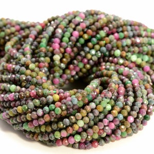 May include: A strand of faceted gemstone beads in shades of green, pink, and purple. The beads are small and round, and they are strung together on a clear thread.