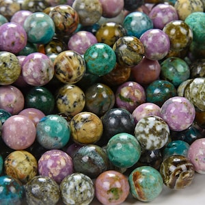 Puede incluir: Una hebra de cuentas redondas de piedras preciosas multicolores. Las cuentas son una mezcla de verde, marrón, rosa y blanco con un aspecto moteado y veteado.