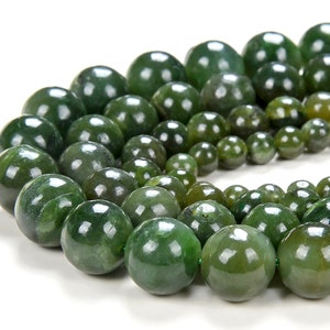 Könnte beinhalten: Eine Reihe runder, grüner Jadeperlen. Die Perlen sind in verschiedenen Größen und auf einem durchsichtigen Faden aufgefädelt.