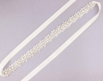 May include: A bridal belt featuring a central band of sparkling rhinestones and crystals. The embellishment is set on a sheer backing and is attached to long, ivory-coloured satin ribbons. Ideal for weddings and special occasions.