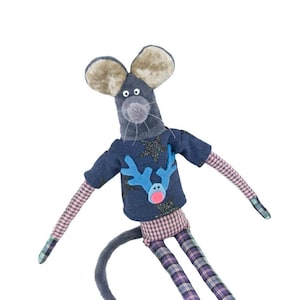 Puede incluir: Un juguete de peluche de ratón gris que lleva una camisa azul con un diseño de reno y pantalones a cuadros. El ratón tiene patas largas y una cola larga.