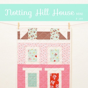 Puede incluir: Un bloque de colcha rosa y blanco que representa una casa con un techo marrón, ventanas y una puerta roja. El bloque de colcha mide 15 pulgadas por 20 pulgadas y se titula "Notting Hill House Mini #103".
